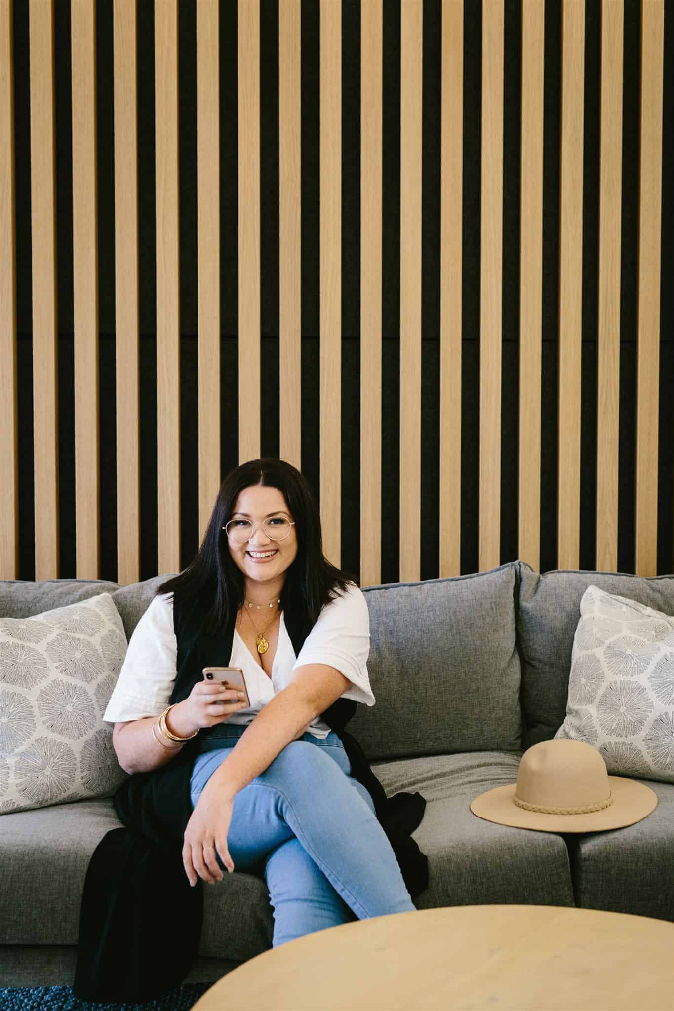 A woman relaxing on a couch in front of a striped wall for Gold Coast brand design.
